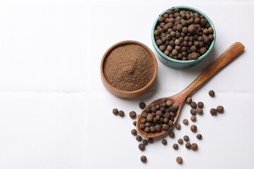 Ground and whole allspice berries (Jamaica pepper) on white tiled table, flat lay. Space for text