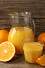 Tasty fresh oranges and juice on wooden table, closeup