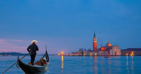 Zelfklevend Fotobehang Venetian gondolier punting gondola through grand canal waters - View of San Giorgio Island in Venice with wooden buoys in Giudecca Canal  © muratart
