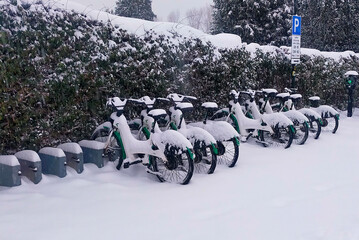 Snow-Covered Bicycles Lined Up at a Public Bike Station