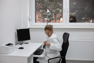 Beautiful female doctor sitting in her office and preparing for work