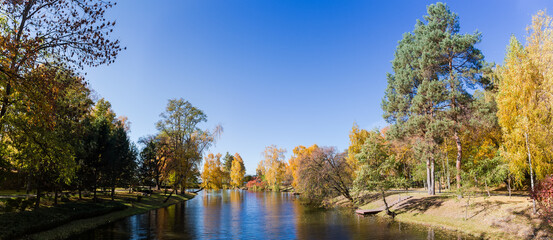 Fototapeta na wymiar Scenic lake with different trees on banks in autumn park