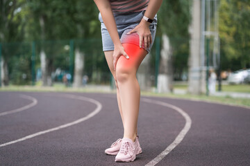 Pain in the hip during training, muscles cramped, massage of female leg on a sports ground after workout - 749944669