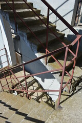 Emergency fire concrete staircase with metal handrails in the sunlight