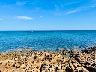 Beautiful azure ocean horizon, rocky coast, clear blue sky