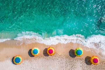 Obraz premium Top-down view of colorful umbrellas lining a sandy beach, meeting the clear turquoise waters.