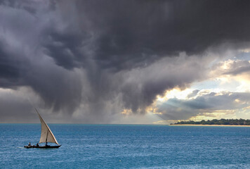 A dhow against thunder clouds, photographed on the Tanzanian coast, East Africa. - obrazy, fototapety, plakaty