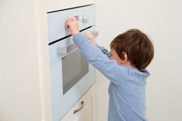 Fototapeta na wymiar Child opening the oven in the kitchen at home. Focus on hand. Kid aged two (two year old)