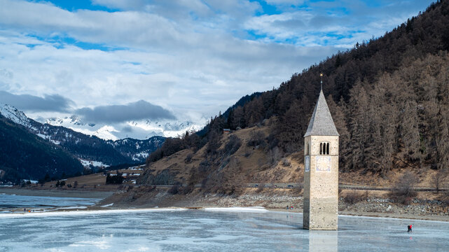Curon, submerged bell tower of Resia. In winter with the frozen lake.