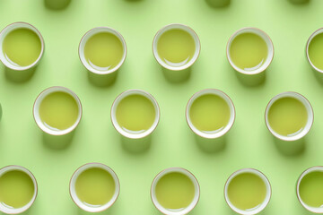 Pattern of Several cups of green tea arranged on green background, top view and it looks beautiful