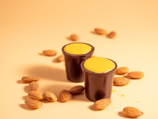 Vanilla pudding in a glass of chocolate on an orange background. Chocolate with vanilla pudding and nuts.