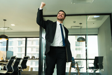 Man in a suit raising his arm and celebrating he just got a salary raise