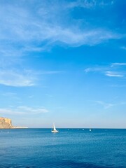 White sail boats at the ocean, blue ocean horizon, rocky coast