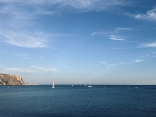 Fototapeta premium White sail boats at the ocean, blue ocean horizon, rocky coast