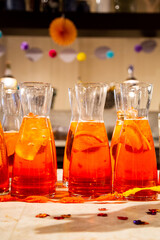 Vivid Aperol Spritz pitchers with orange slices on party table with festive background