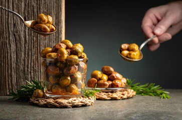 Spicy olives in a glass bowl on a stone table.