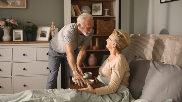 Senior man bringing his wife breakfast in bed