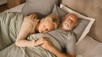 Senior couple sleeping peacefully in their bed
