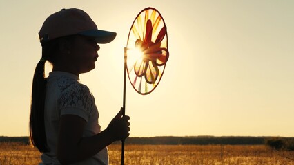 toy windmill sunset, child girl looking sunset holding windmill hand, catching wind glare sunset,...