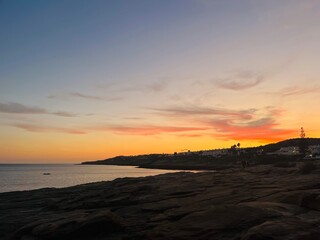 Fototapeta na wymiar Orange sunset at the ocean, rocky ocean bay
