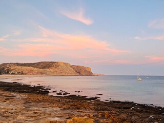 Natural pastel colors of the sky at the ocean, rocky ocean bay, purple heaven 