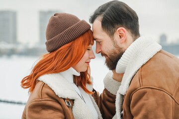 Love romantic couple lovestory. Brutal bearded man, bright red-haired girl woman in winter park....