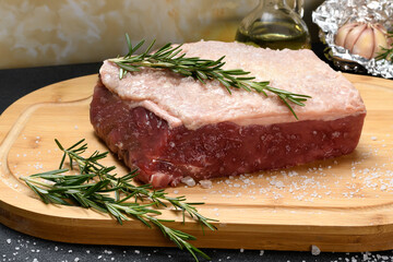 RAW BEEF FILLET WITH SALT AND ROSEMARY ON A CUTTING BOARD