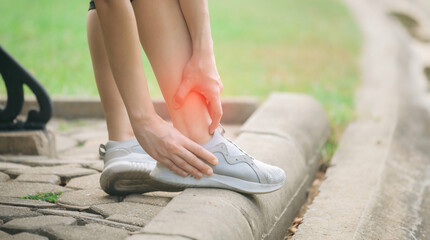 Sprained ankle problem. woman jogger. 30s asian female wearing sportswear holding her ankle with...