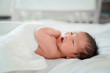 Obraz na płótnie Canvas male newborn baby Is a person of Asian ethnicity Lying in the bedroom on a white bed