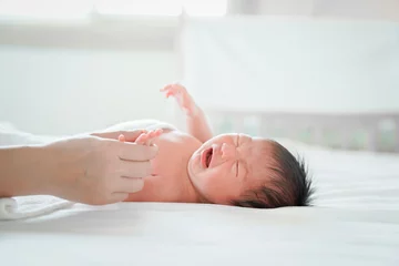 Fotobehang newborn male Is a person of Asian descent Lying in the bedroom on a white bed I'm crying. © SKW