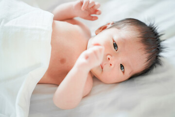 Fototapeta na wymiar male newborn baby Is a person of Asian ethnicity Lying in the bedroom on a white bed