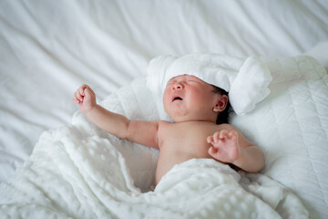 newborn male Is a person of Asian descent Lying in the bedroom on a white bed I'm crying.