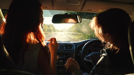 Two happy redhead young female friends dancing having fun driving car road trip closeup back view. Smiling woman relaxing dance music radio automobile journey adventure escape at bright sun light