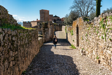 Fototapeta na wymiar Female tourist strolling through the narrow streets of the medieval stone town of Trujillo.