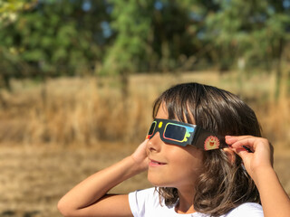 A young girl looking at the sun during a solar eclipse on a country park, family outdoor activity