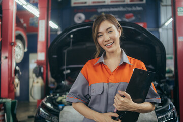 Portrait of Asian woman office employee holding clipboard standing at auto repair shop. Female...