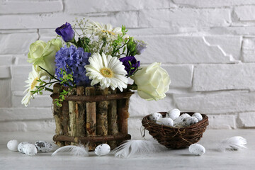 Blumenstrauß  mit Ostereiern
 vor einer weißen Mauer. 
