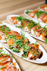 Gourmet Smoked Salmon and Arugula Appetizer. Elegant presentation of smoked salmon topped with fresh arugula and drizzled with balsamic glaze, served as an appetizer.
