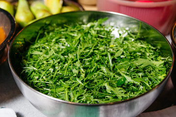 Fresh Washed Arugula Leaves in Large Metal Bowl. A large bowl overflowing with crisp, washed arugula leaves, ready for a healthy salad or as a garnish.