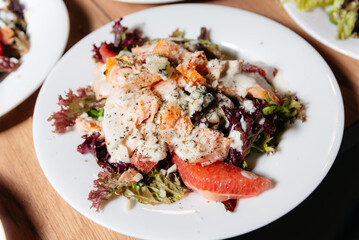 Baked Salmon Salad with Mixed Greens and Grapefruit. A delightful plate featuring flaky salmon over a bed of mixed greens, accented with citrus segments and a creamy dressing