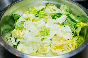 Fresh Chopped Lettuce in Stainless Steel Bowl. Freshly chopped green lettuce in a shiny stainless...