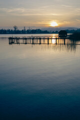 Naklejka premium As the sun begins its descent, the lake takes on a golden glow, the reflection of the fading day painting the waters with warm hues. 
