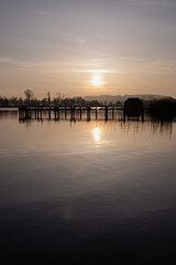 As the sun begins its descent, the lake takes on a golden glow, the reflection of the fading day painting the waters with warm hues. 
