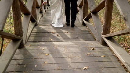 The newlyweds go down the steps. Taking the first step into family life. The feet of the bride and groom walk along the wooden steps. Bride and groom.
