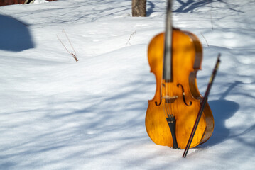 a cello and a bow abandoned on the snow, winter scene, no people