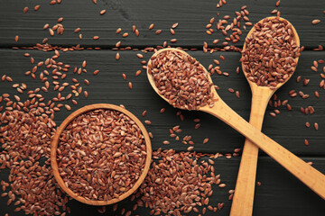 Flax seeds on wooden bowl and spoon on black background