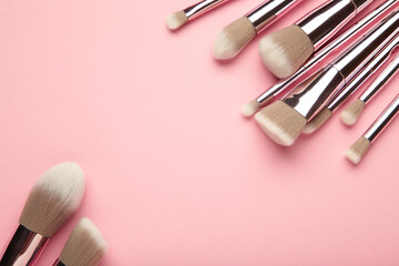 Set of makeup brushes on pink background. Top view. Space for text