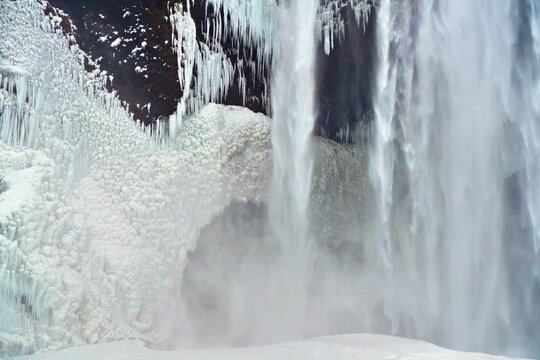 Winter waterfall with ice formations and mist Location: Skogafoss Waterfall Iceland.
