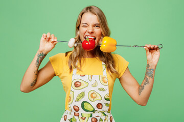 Young happy housewife housekeeper chef cook baker woman wears apron yellow t-shirt hold skewer with...