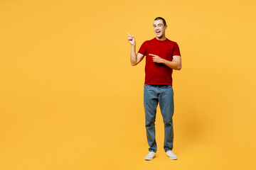 Fototapeta na wymiar Full body smiling fun young middle eastern man he wear red t-shirt casual clothes point index finger aside on empty area isolated on plain yellow orange background studio portrait. Lifestyle concept.